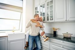 Woman sitting on kitchen counter holding her husband from behind