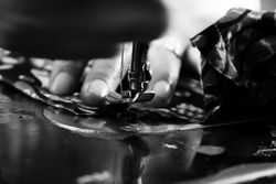 Close up of hands putting fabric under sewing machine needle