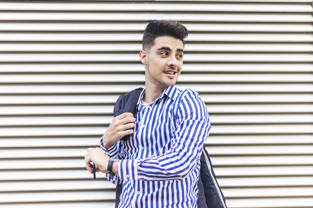 Young man standing outdoors and looking behind him