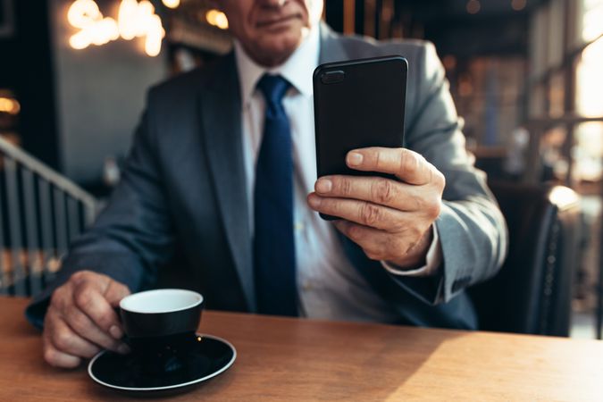 Mature businessman using smartphone at coffee shop