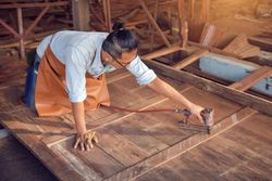 Carpenter drilling a screw into a wooden plank