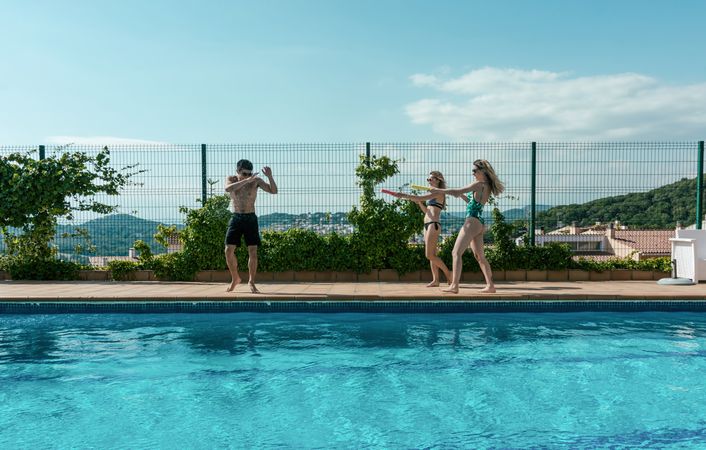 Friends playing with water pistols in the pool