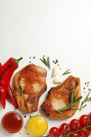 Vegetables and fried steaks on light background, top view
