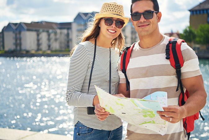 Smiling couple standing near river with map