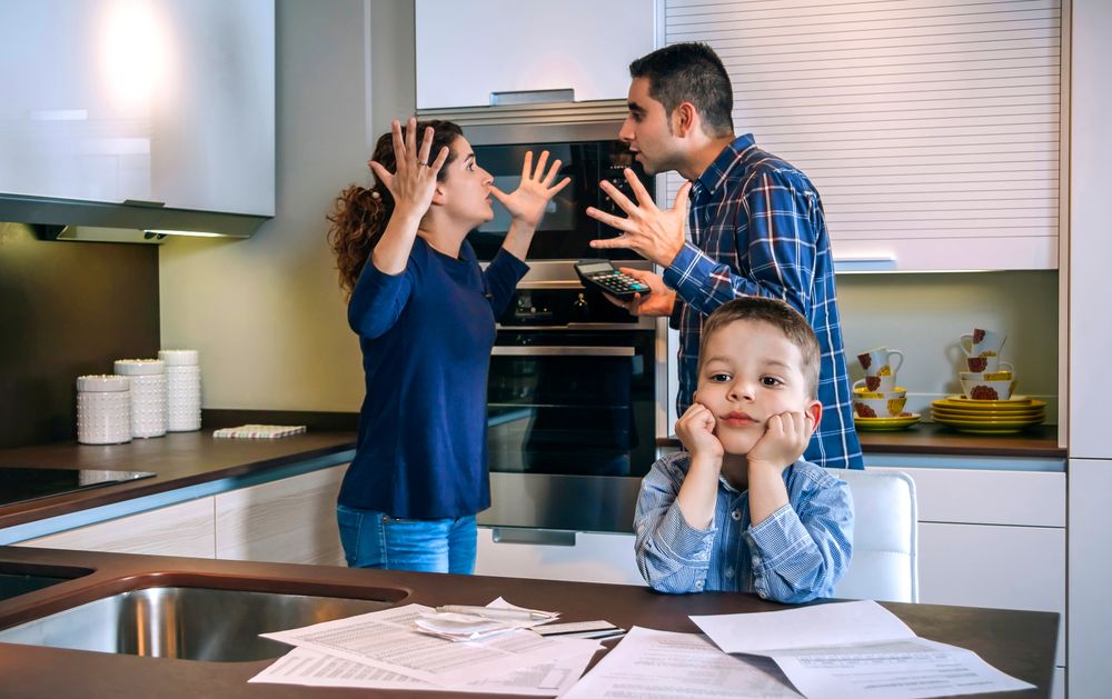 Man and woman with hands up in frustration as they argue in front of their son