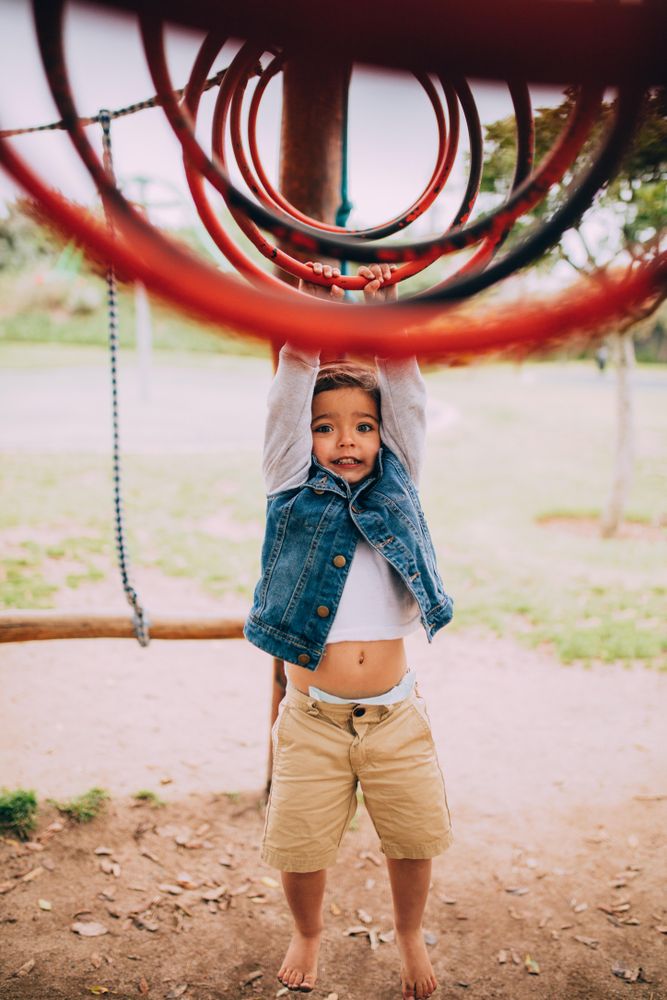 Toddler hanging on a jungle gym at a playground