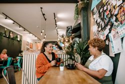 Older Black woman smiling at daughter at cafe