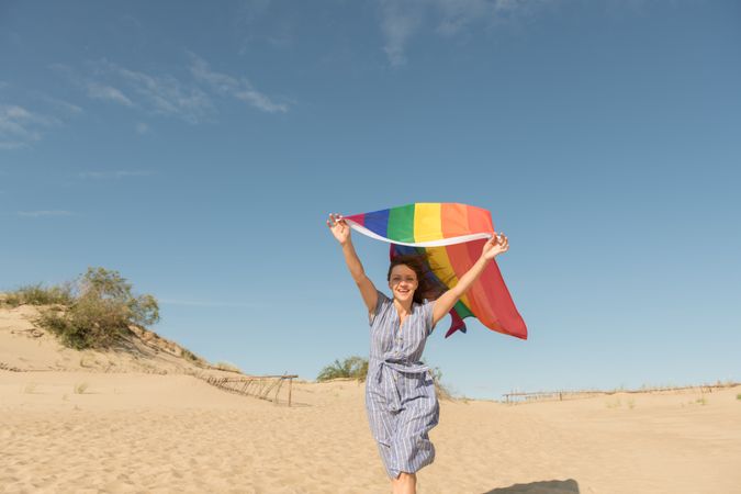 Young woman with rainbow banner against sky