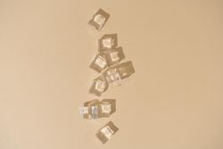 Flat lay of ice cubes on beige background with shadows