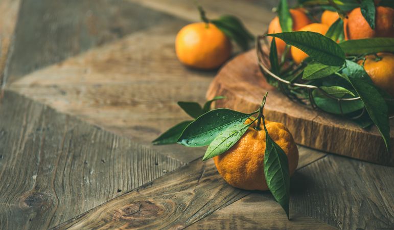 Freshly picked tangerines with leaves on wooden table with copy space