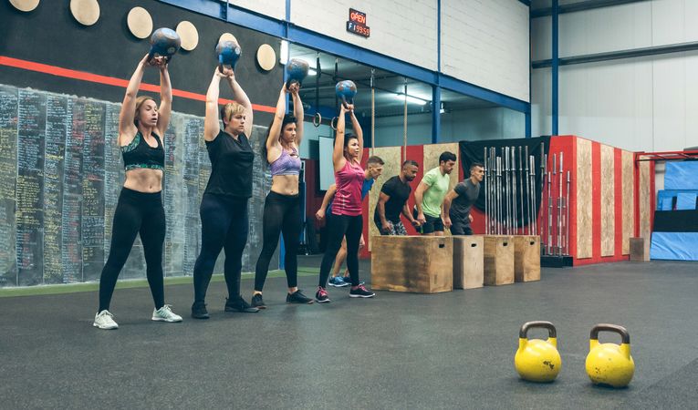 Sportswomen with kettlebells and sportsmen in background