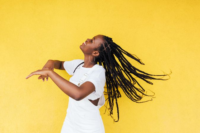 Smiling Black woman with long braids dancing outside