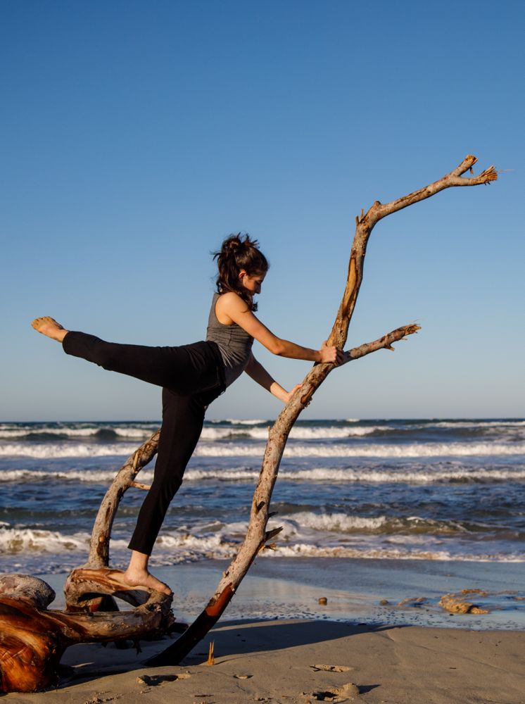 Young woman dancing and posing near water on shore