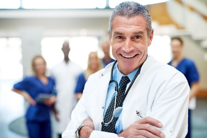 Portrait of smiling mature doctor in lab coat and stethoscope
