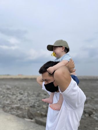 Father holding baby over his shoulder outdoor