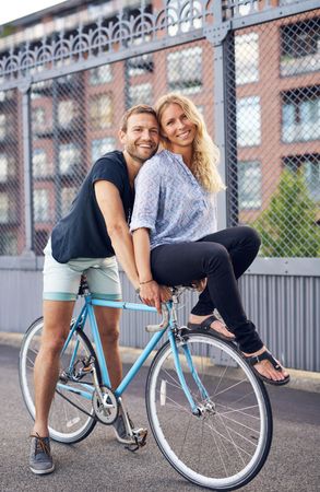 Couple smiling at camera while sitting on bicycle together