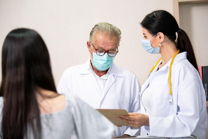 Two medical colleagues in face masks discussing patient chart