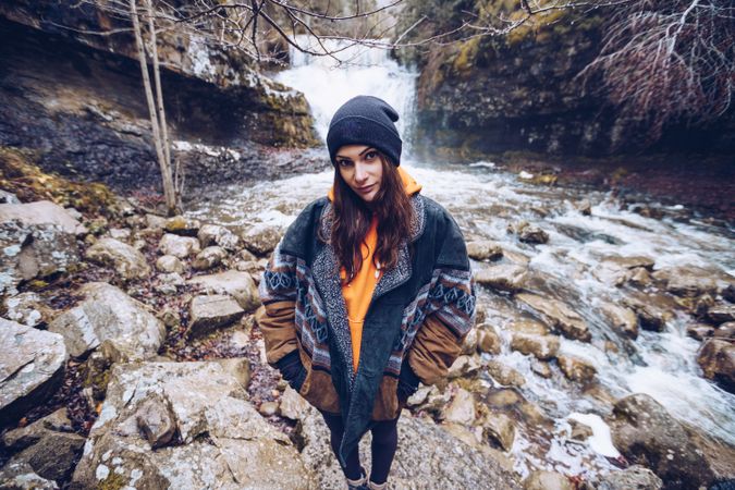 Woman standing at fast mountain river in forest