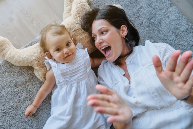 Cheerful mother and daughter lying on carpet