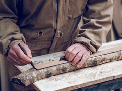 Faceless carpenter making marks on wood