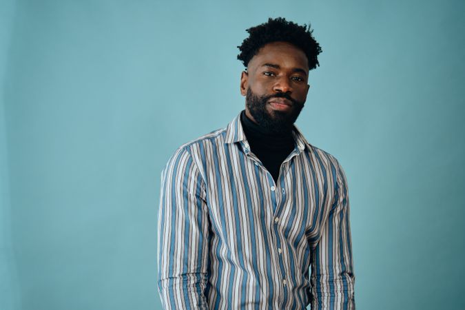 Serious Black man in striped shirt in blue studio shoot
