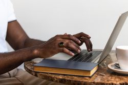 Black man using laptop at table in cafe