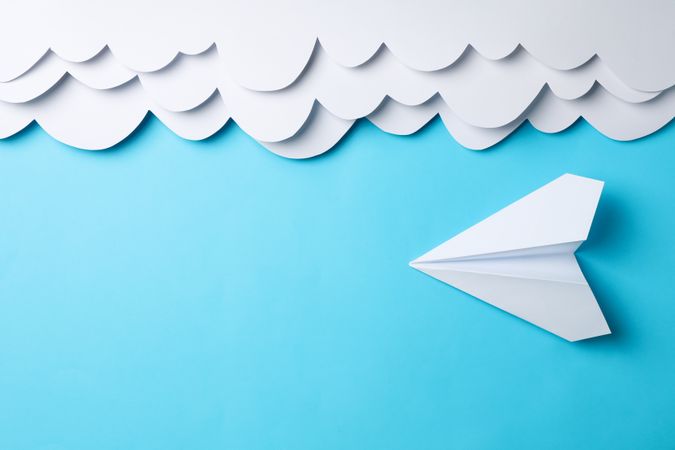 Paper clouds and plane on blue background. Travel