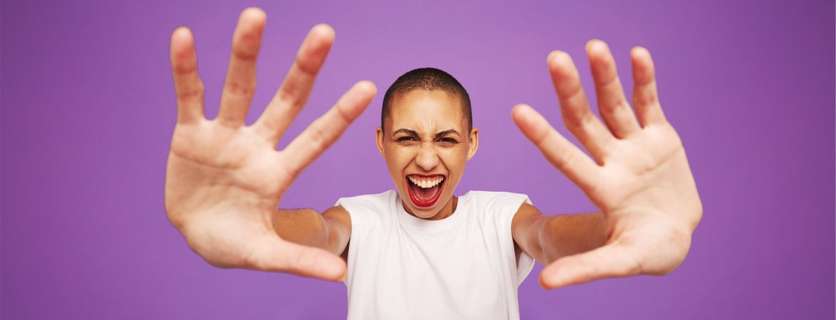 Female model with shaved head and hands in front