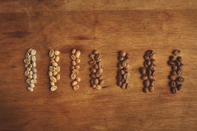 Different grades of coffee beans organized on rustic aged table, close up, top view