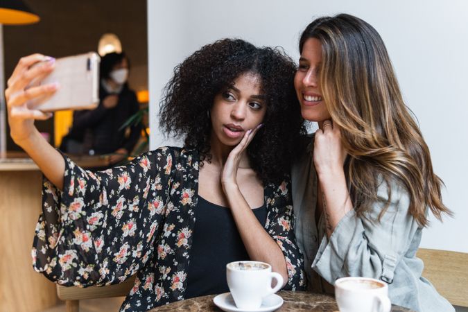 Multiracial girlfriends taking selfie on smartphone