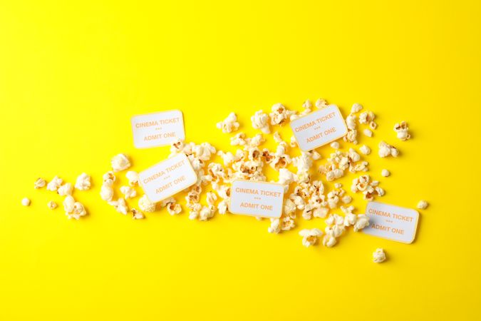 Flat lay composition with popcorn and tickets on yellow background