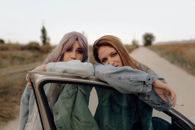 Modern women with cigarette near car in nature