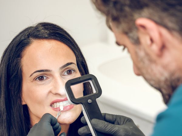 Dentist checking teeth shade of female patient
