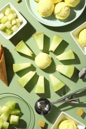 Ice cream scoops with slices of fresh melon on a green background