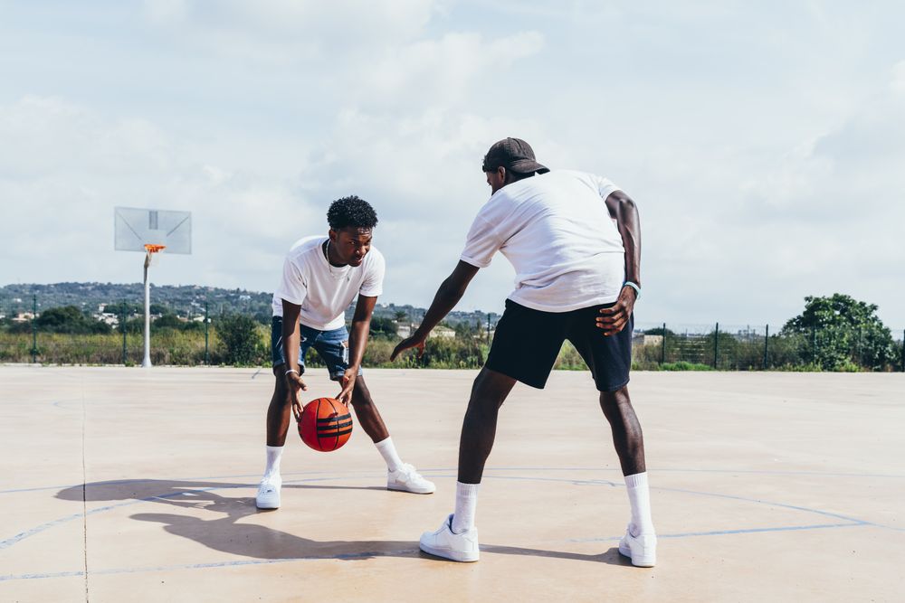 Black friends playing basketball in bright day