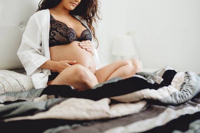 Female expecting baby sitting on bed