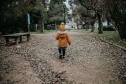 Back view of child in winter clothes walking away