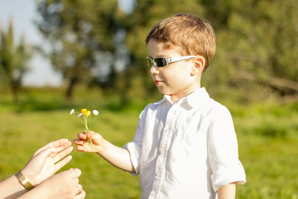 Son giving a bouquet of flowers to his mother in a field