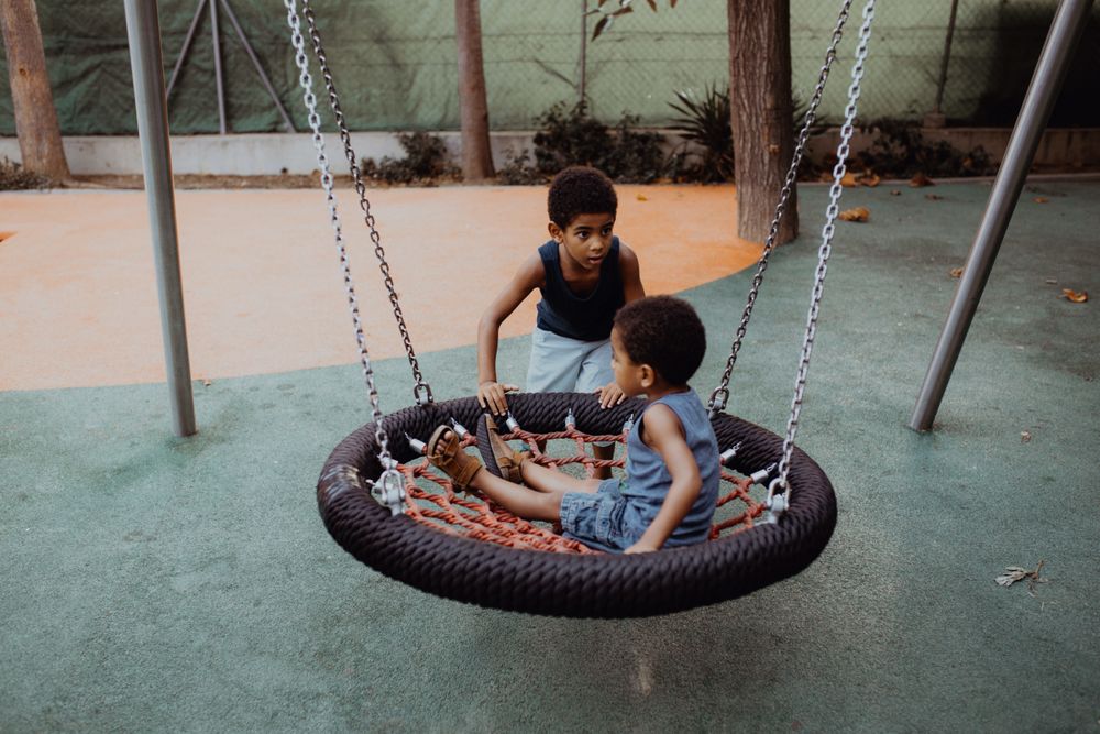 Black boy swinging little brother