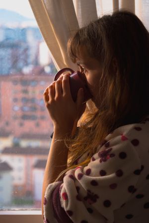 Woman enjoying hot beverage near fridge