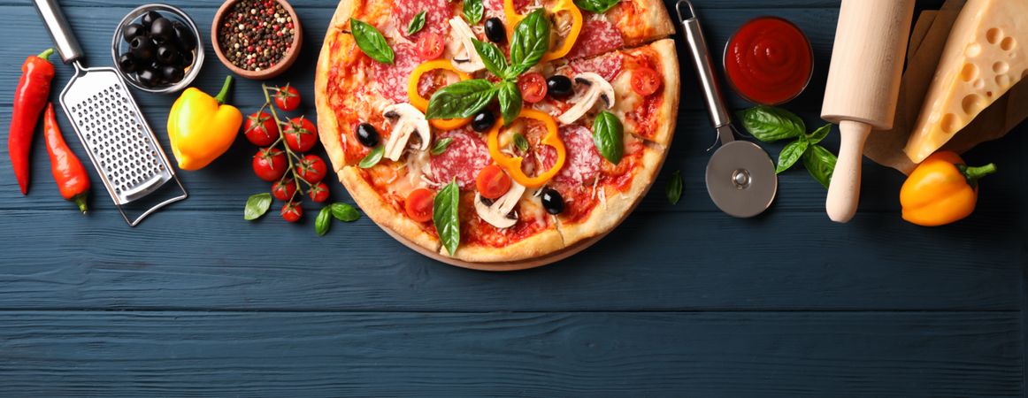 Delicious pizza and ingredients on wooden background, copy space
