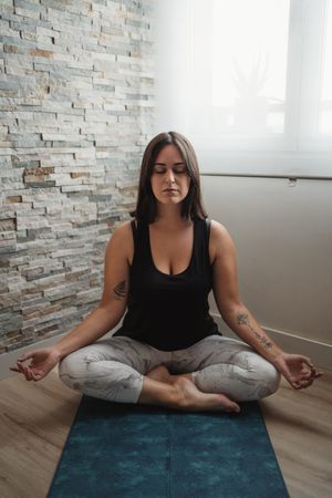 Woman in lotus pose meditating at home