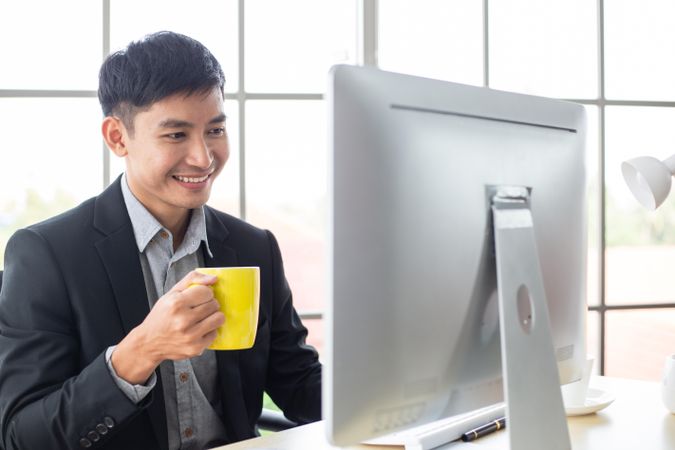Male employee smiling looking at screen in the office
