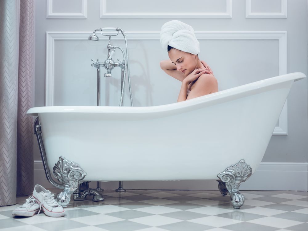 Young woman with towel on head in bathtub
