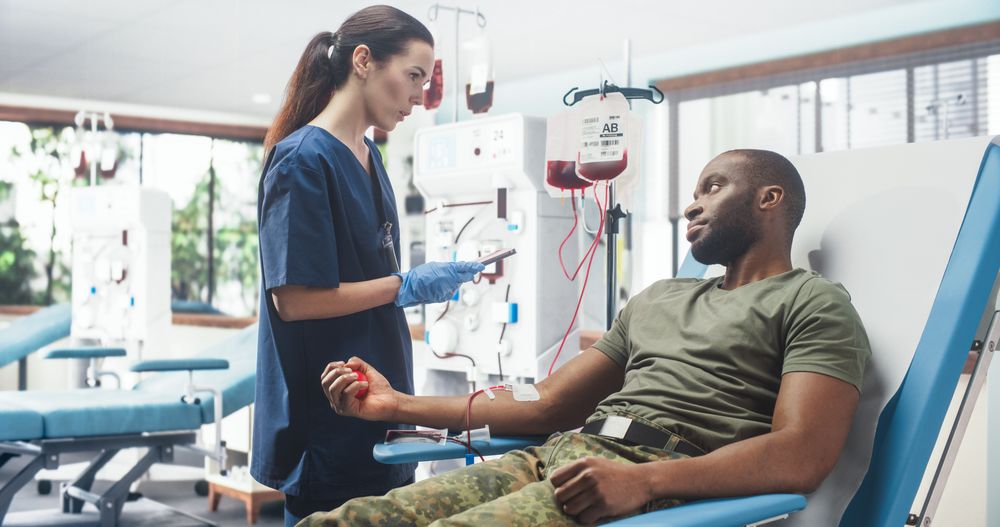 Female Nurse Taking Blood Donation From Black Army Soldier In Military Hospital.