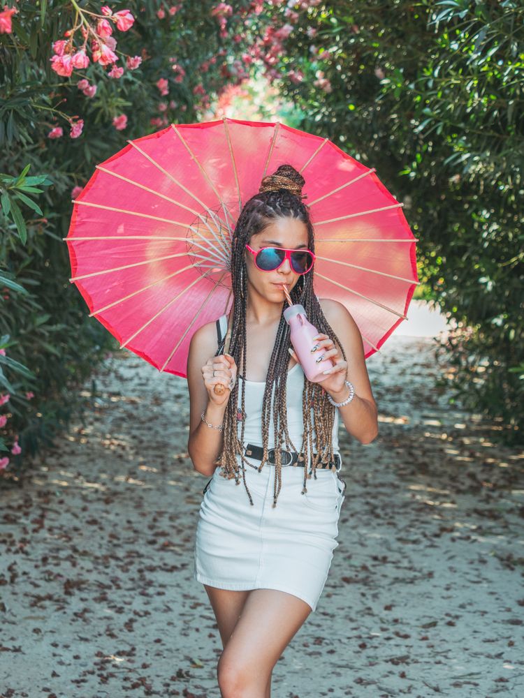 Female with umbrella standing near blooming trees
