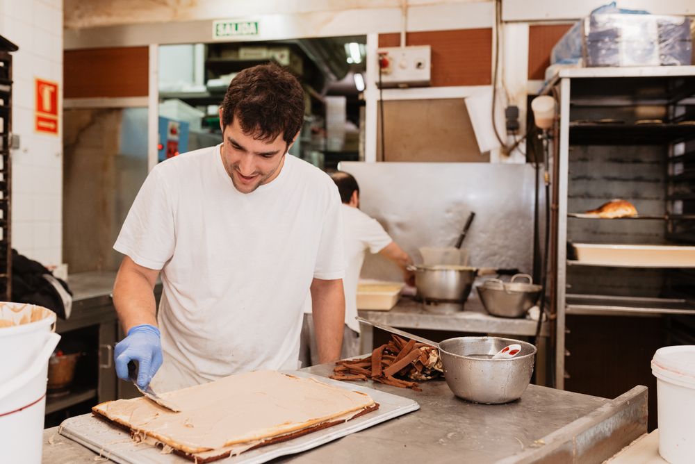 Male confectioner preparing cake in kitchen