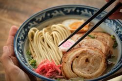 Crop person having delicious ramen soup