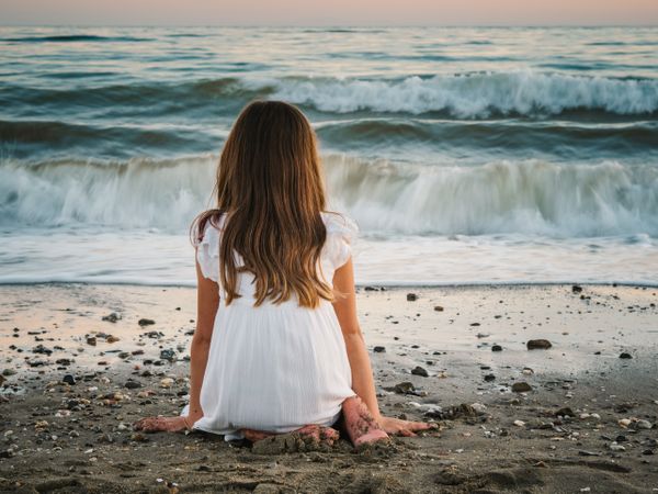 back view girl sitting on beach in daylight