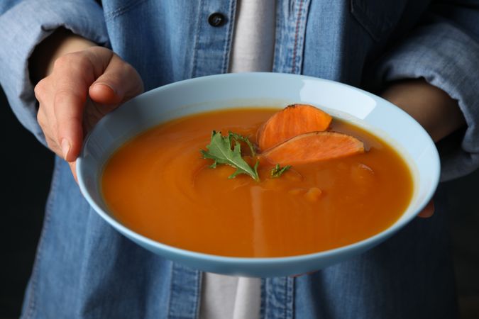 Person holding bowl of sweet potato soup